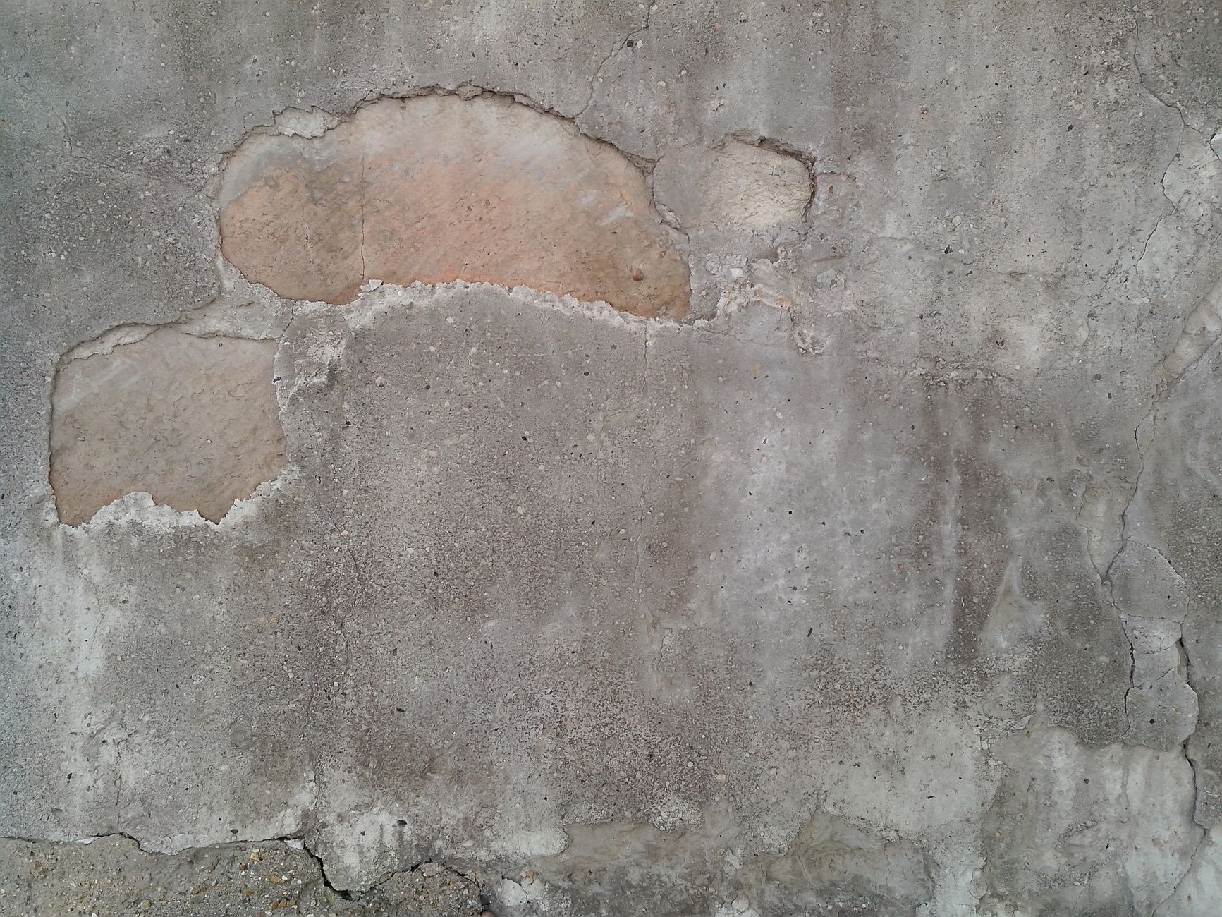 Close-up of a weathered concrete wall with grunge texture and exposed patches in Riverside, CA